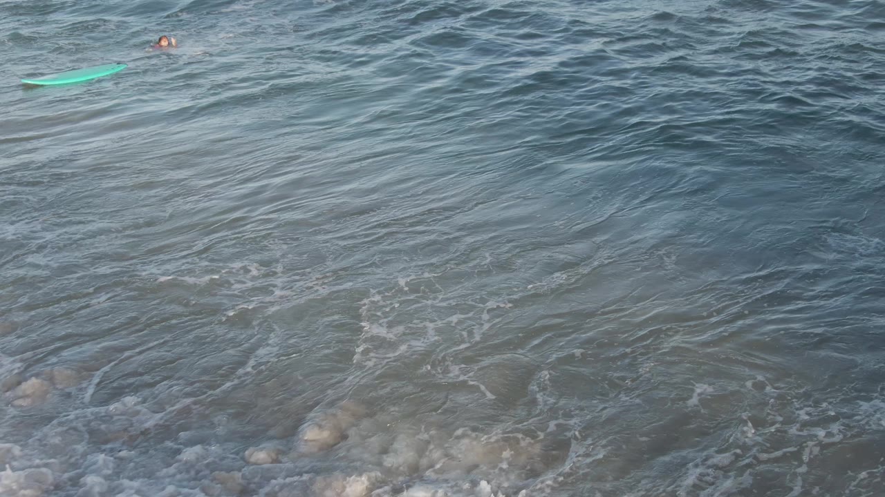 Green bodyboard and swimmer in open textured ocean water.