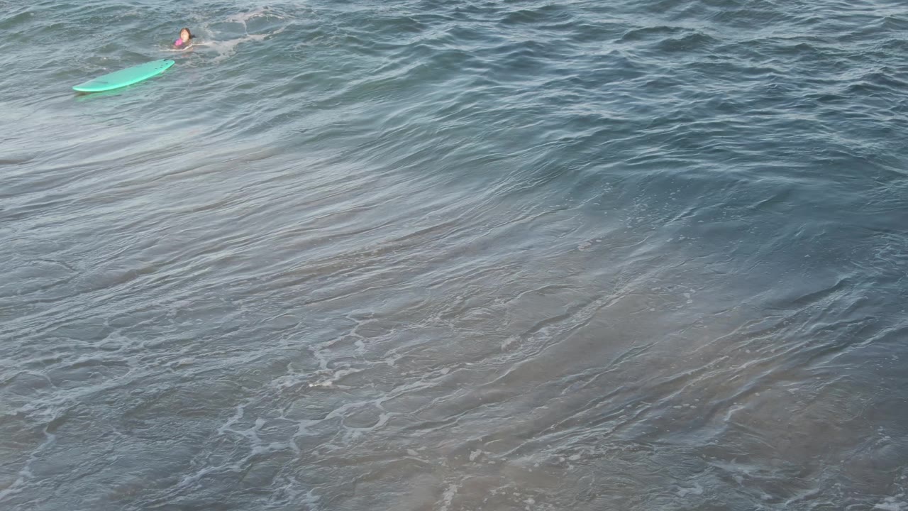 At Costa Azul Los Cabos, the bodyboarder appears near the upper right as a broad diagonal wave face rolls through textured blue green water.