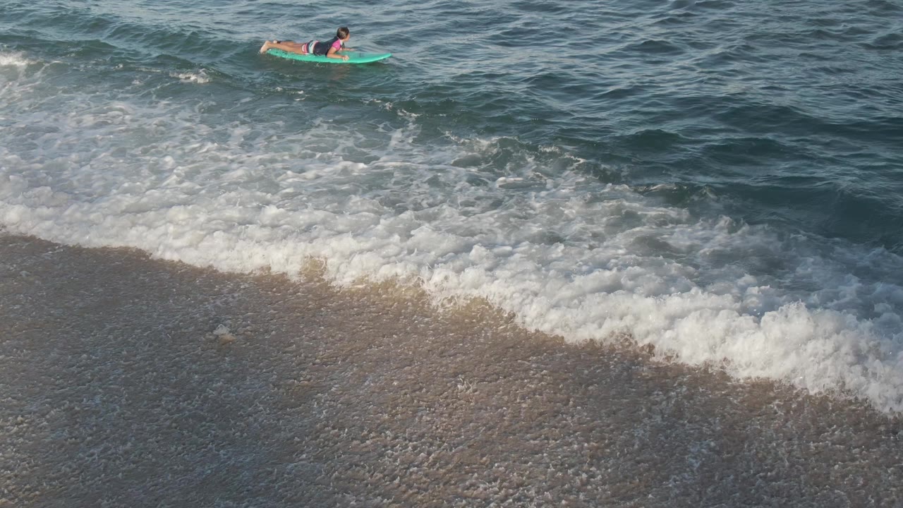 At Costa Azul Los Cabos, the rider remains offshore near the upper frame while a broad band of white surf curls across the sandy shoreline.