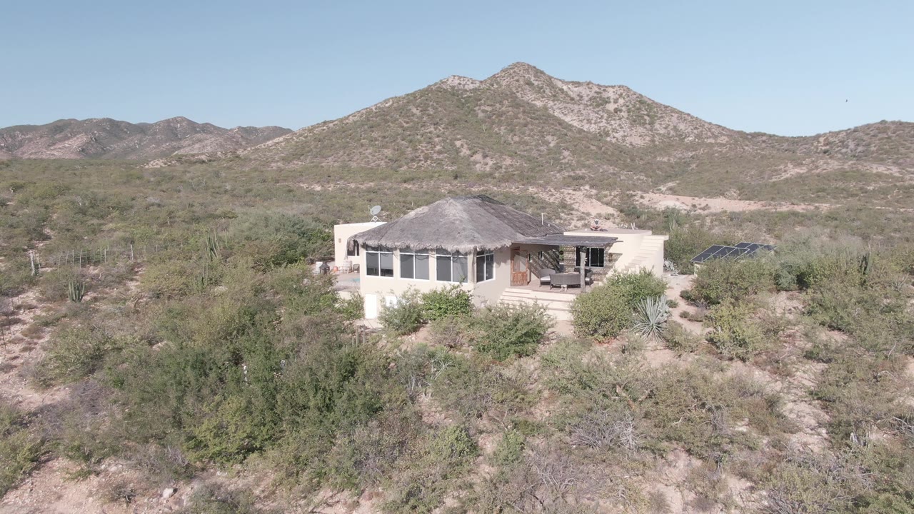 Desert residence viewed from above with foreground brush and hills