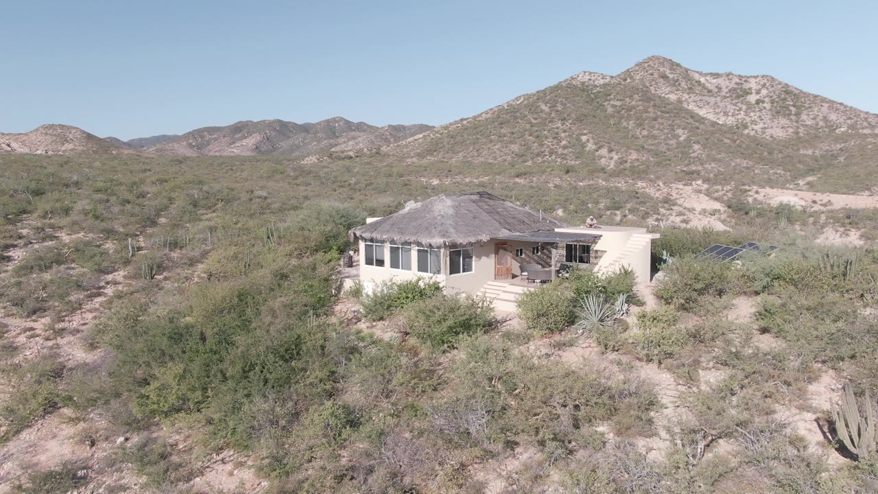 Desert home with brushy foreground and mountains
