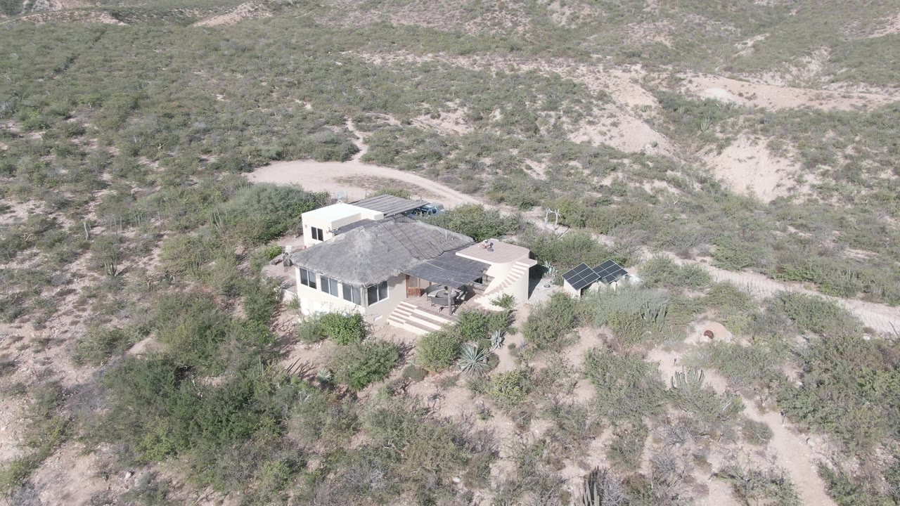 Overhead desert landscape with a house, shrubs, cacti, and sandy access paths.
