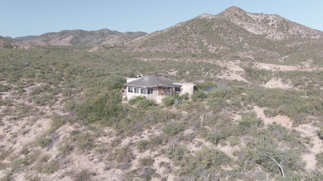 Remote house amid desert brush and sandy gullies.