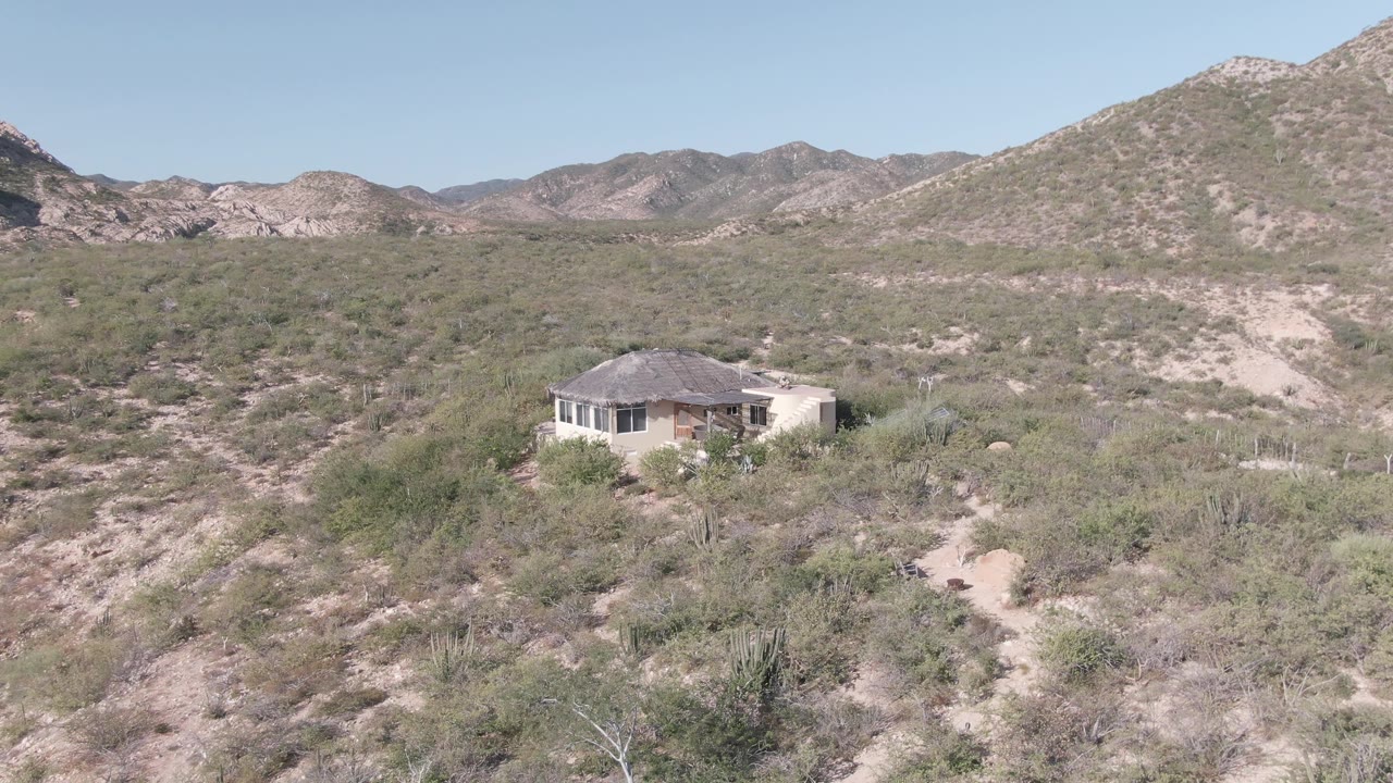 Closer view of desert house and surrounding brush