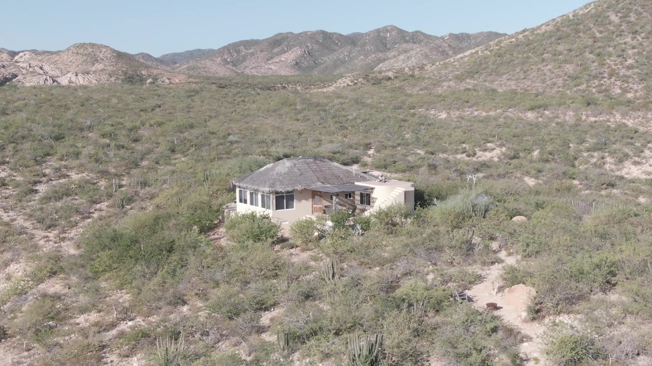 Wide desert landscape with small house and mountains