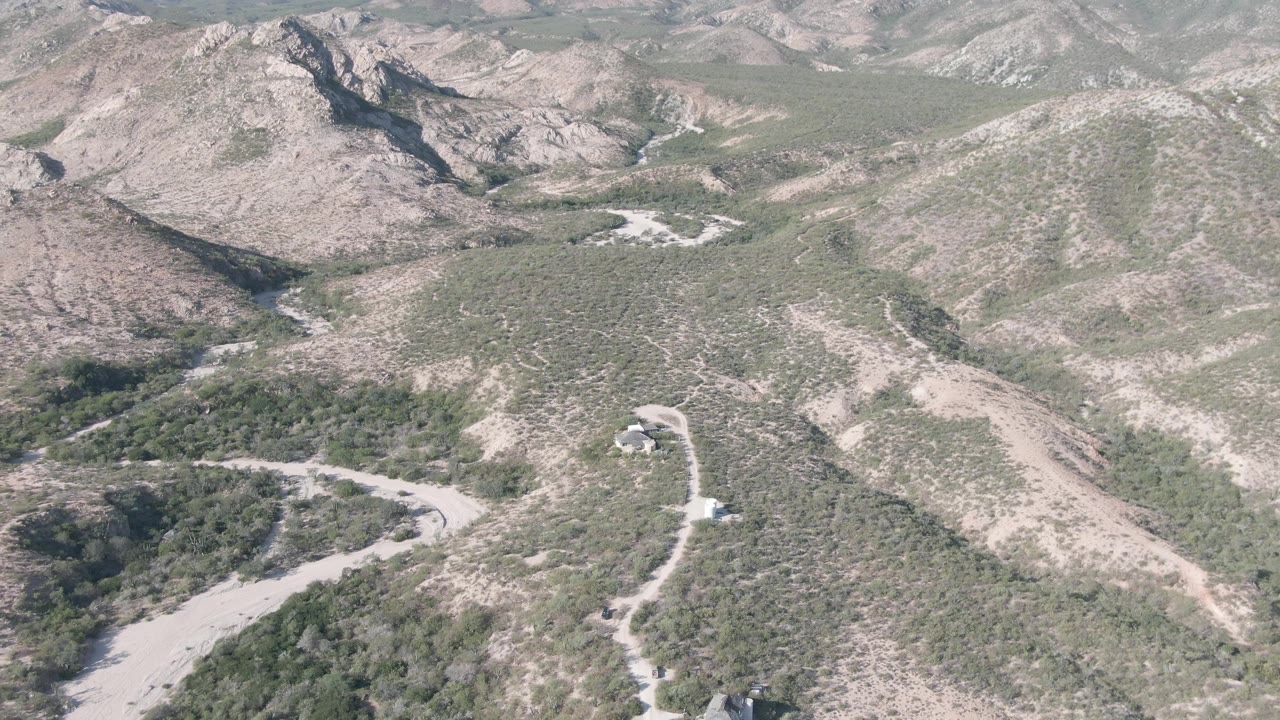 Aerial view of rocky hills and a winding dirt road under clear sky.