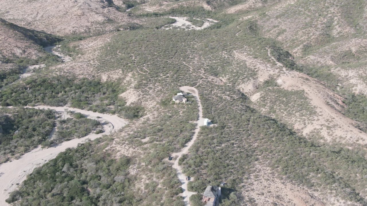 Elevated view of scrubby hillsides crossed by a pale dirt road.