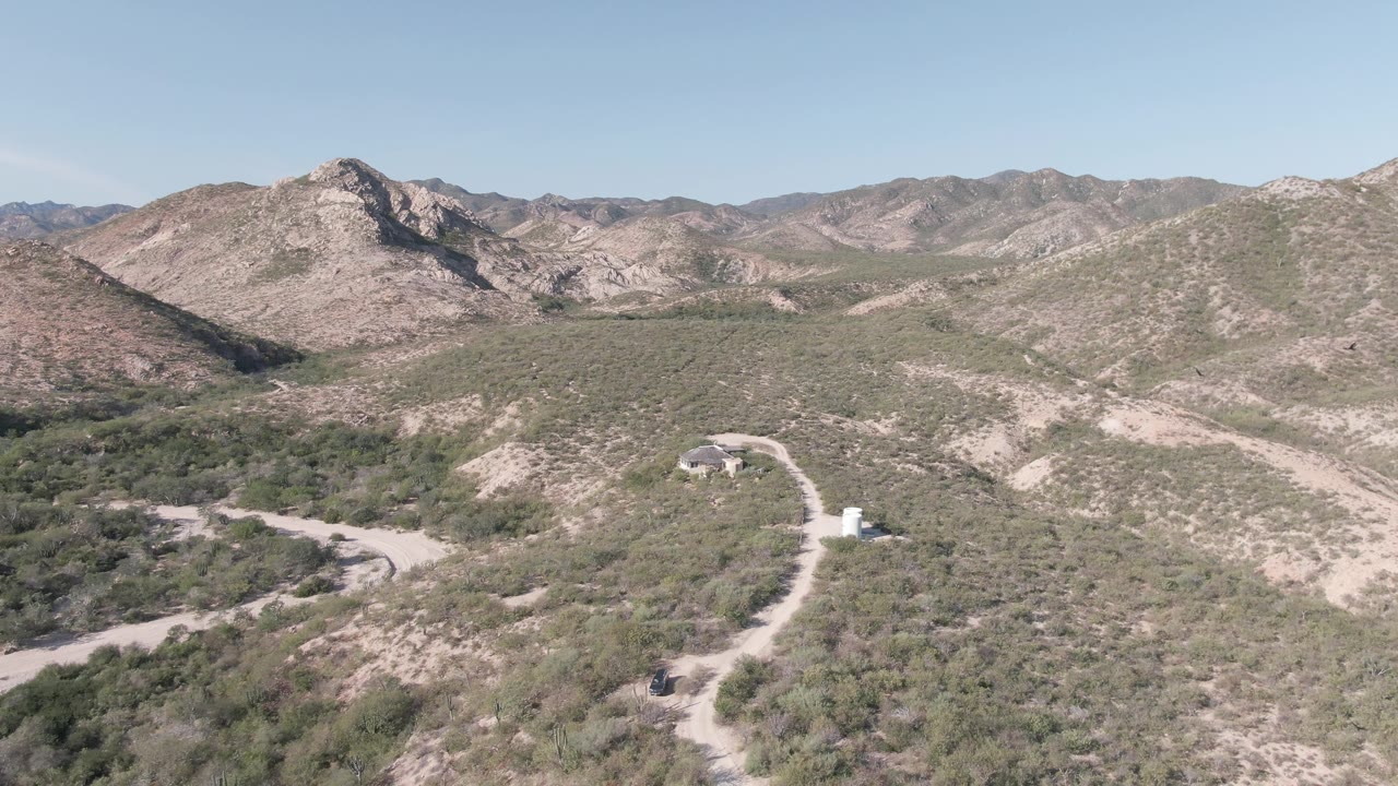 Small vehicle on a winding dirt road in scrubby desert hills