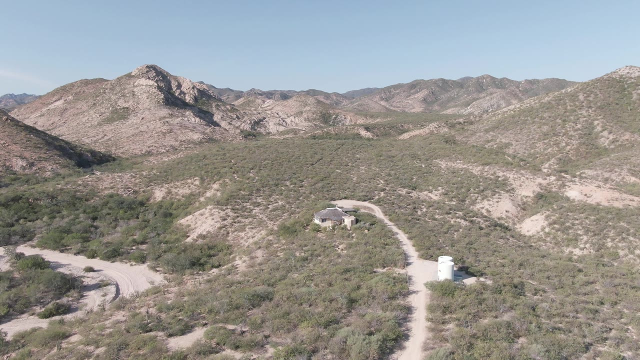 Desert mountain aerial view with dirt roads and small structures after the eagle passes.