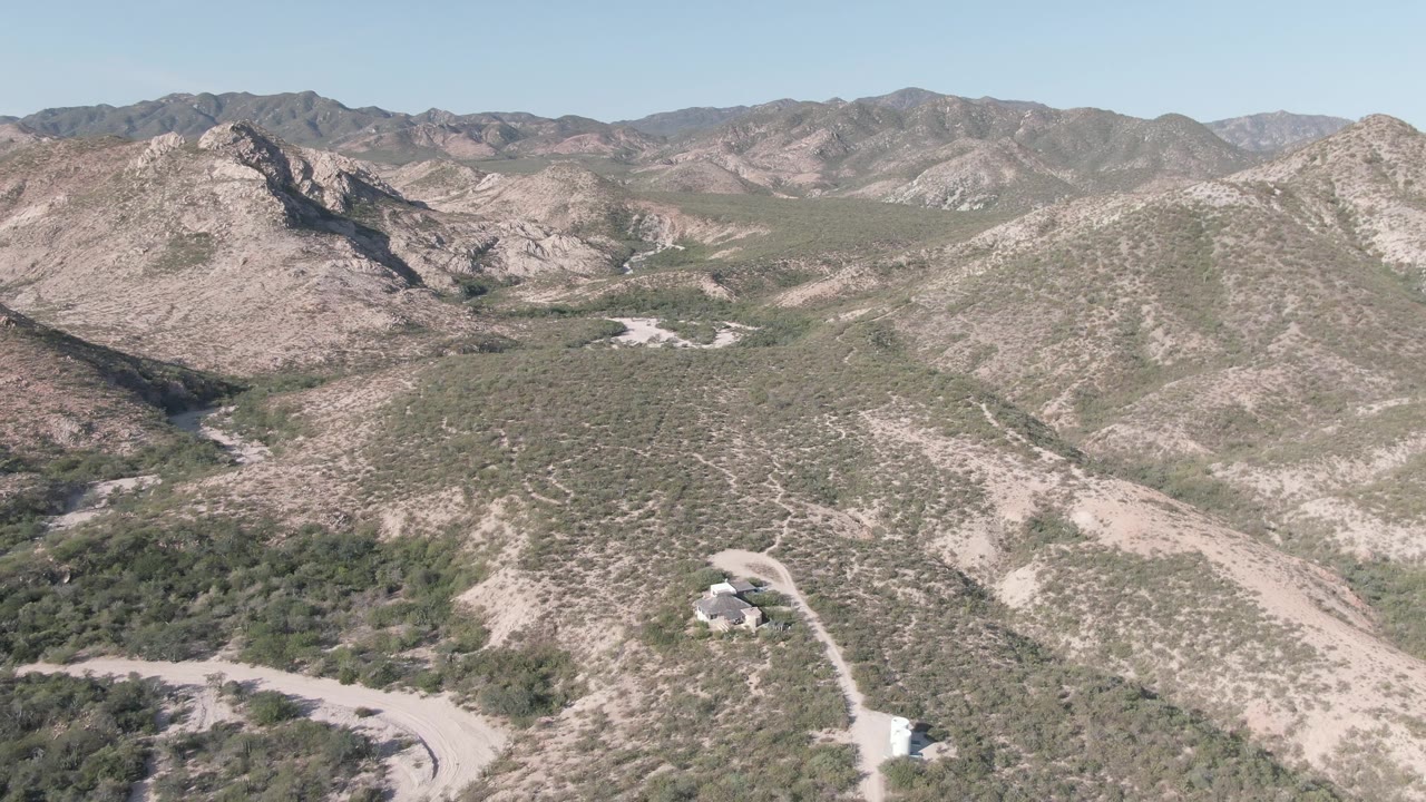Aerial desert mountain view with winding dirt road and scrub vegetation.
