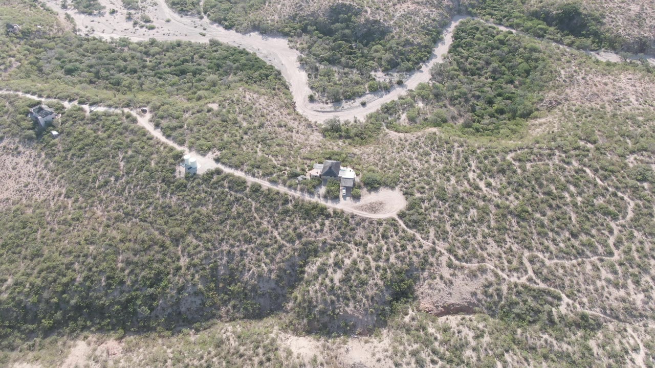 Aerial frame from Cabo Pulmo, Baja California Sur with the road and trail network running across a scrubby slope, small structures set near the paths, and no visible people.