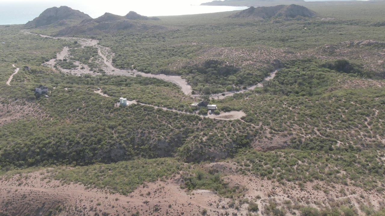 Closer aerial view of a winding dirt road through scrub-covered hills