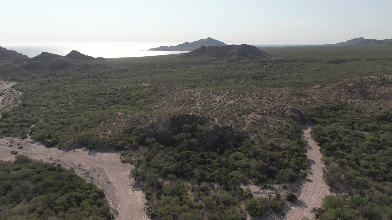 Elevated view of a winding dirt road through green coastal hills