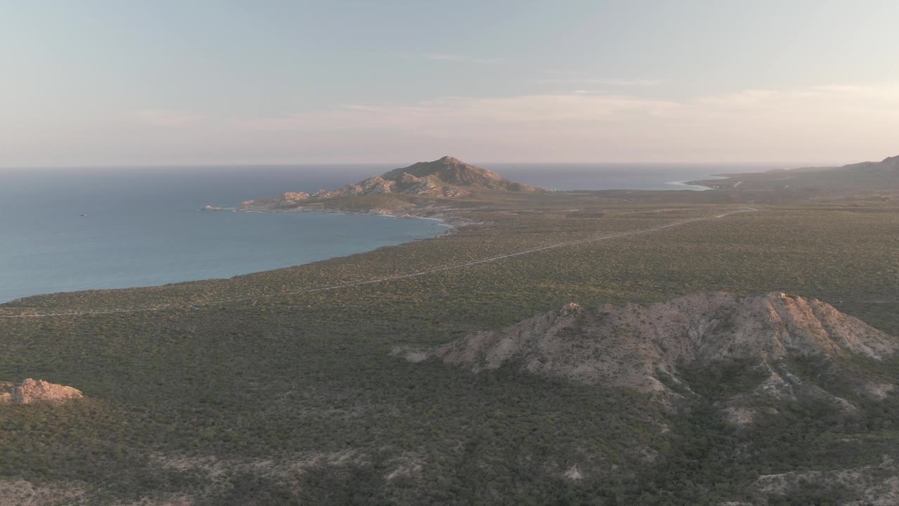 Wide aerial coastal landscape with scrub hills and blue water
