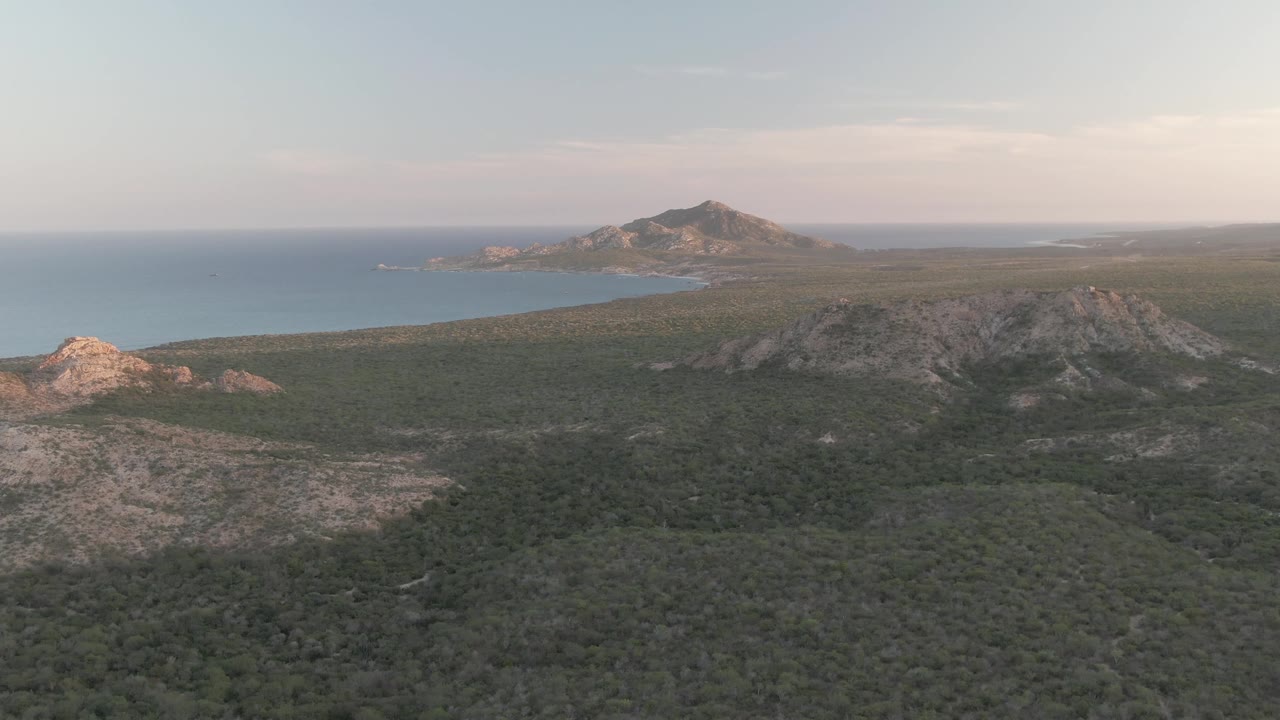 Aerial view of rocky green hills leading to a blue coastal bay.