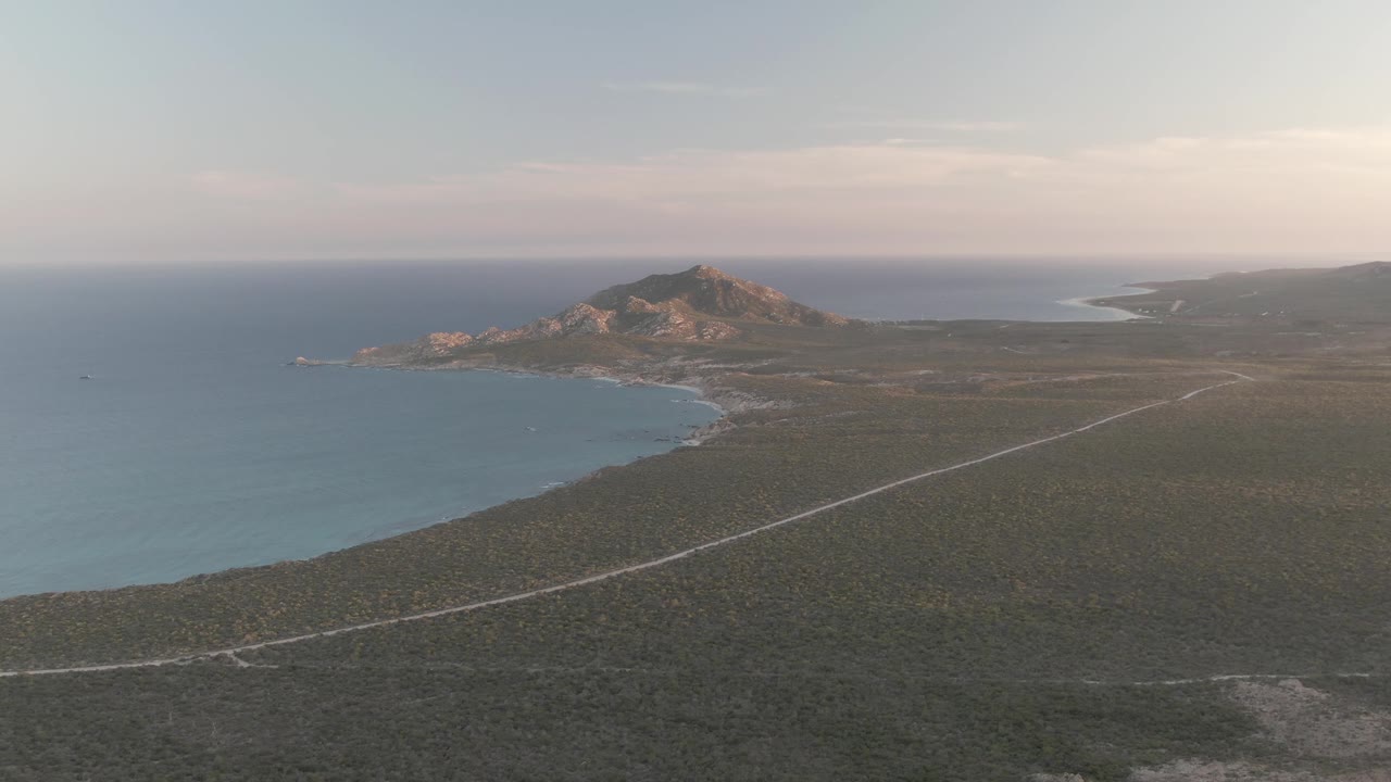 Aerial coastal road beside ocean and rocky hills