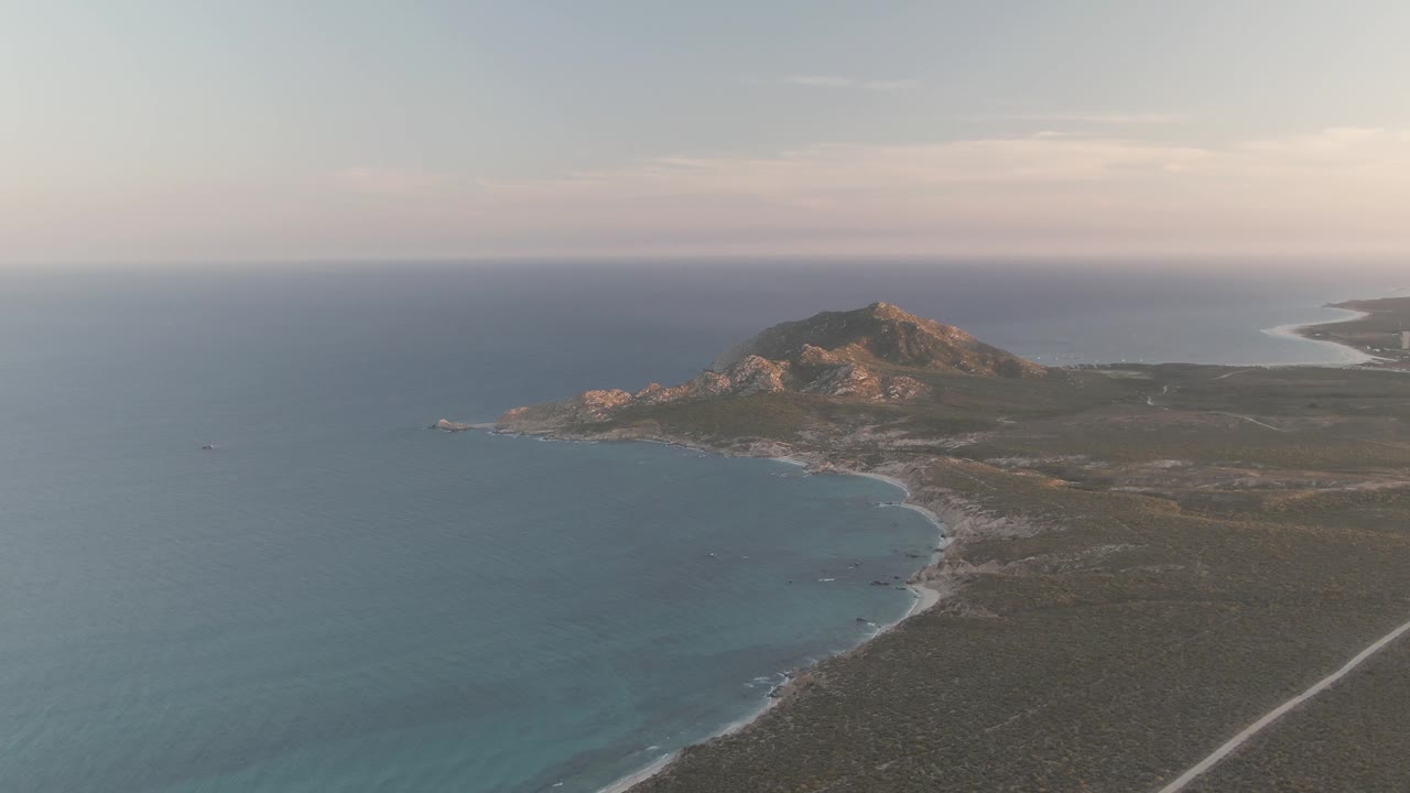 At 0:02 the Cabo Pulmo coast shows a broader sweep of blue water, the beach bending around the bay, the road cutting through scrubland, and no visible people.