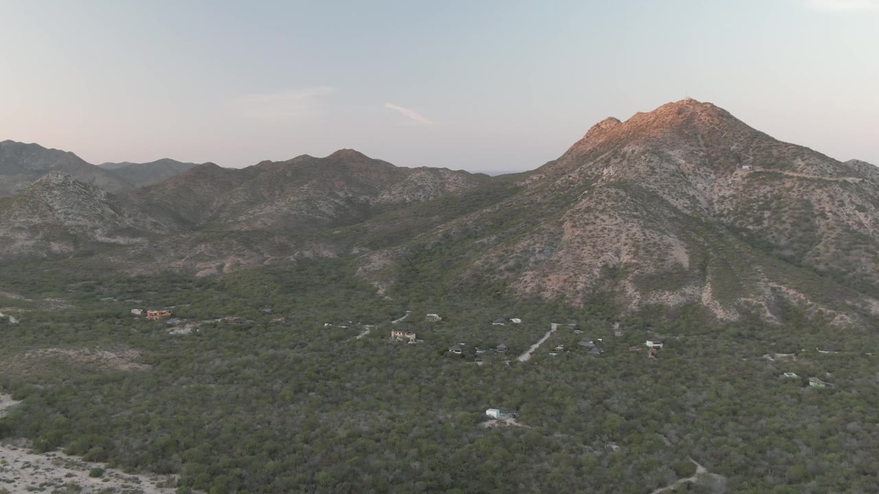 Aerial view of mountains and a tree-covered valley under soft evening sky.