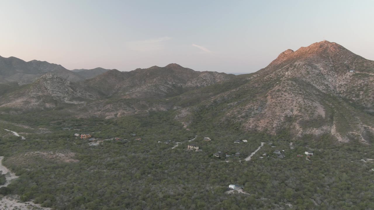 Mountain ridge above dense greenery with small buildings spread through the valley.