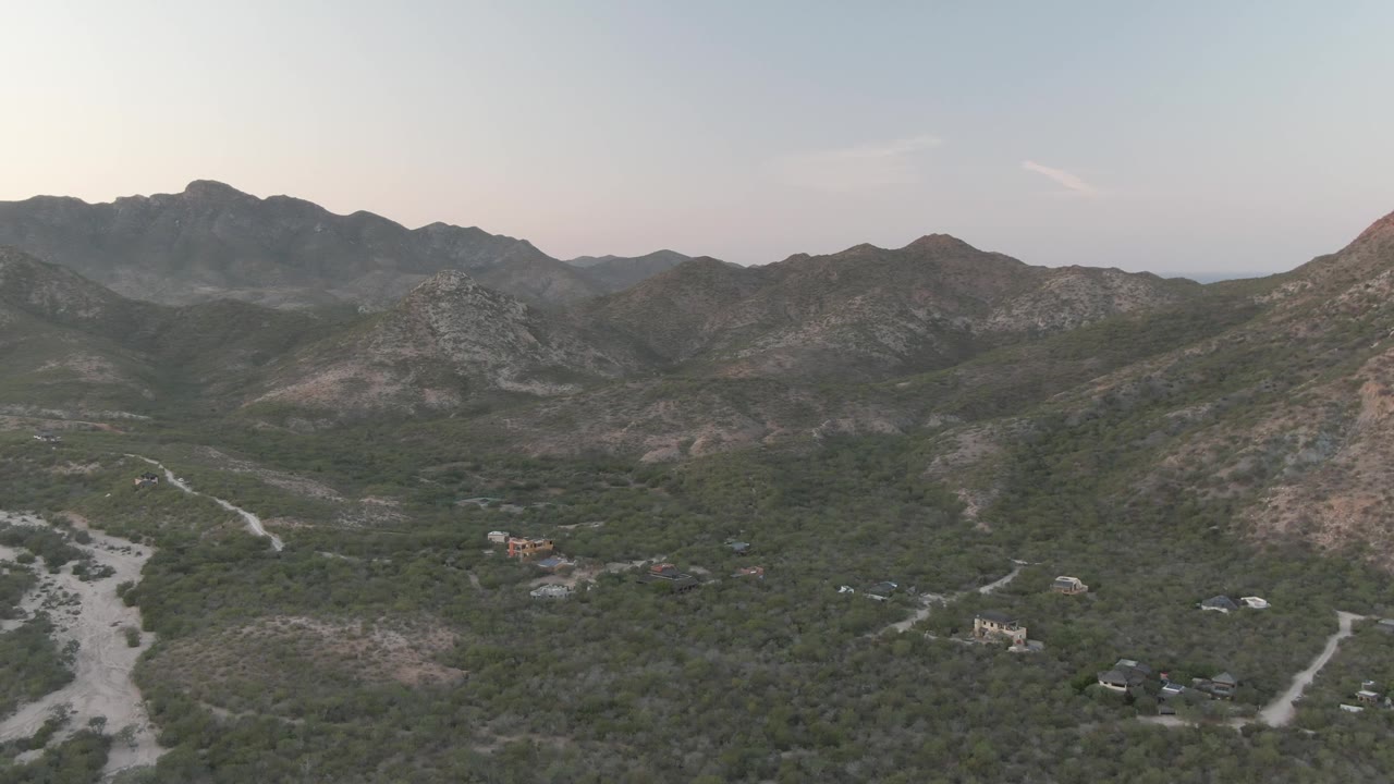 High aerial view of dry mountain slopes with a pale road branching through the valley.