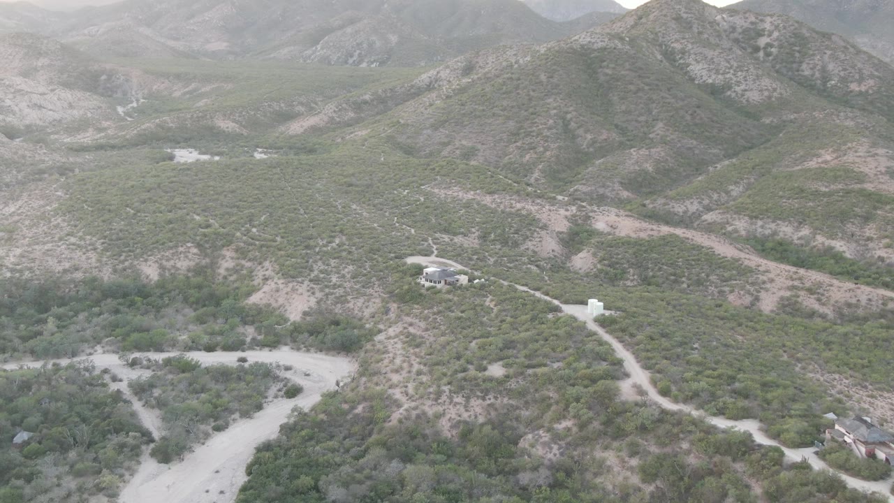 Scrub hills with winding dirt tracks and isolated buildings below