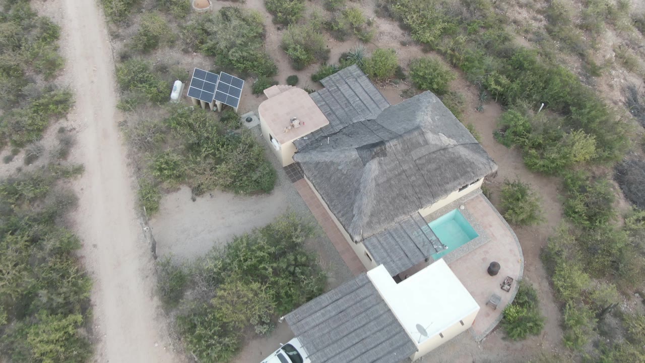 White SUV begins appearing under the carport beside the desert house.