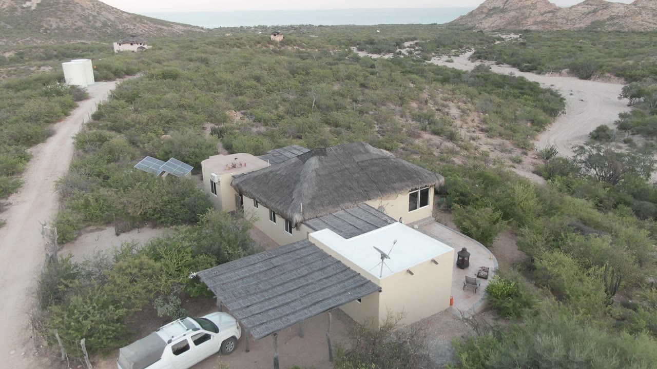 Aerial view of desert house as the SUV nears the lower edge of frame.
