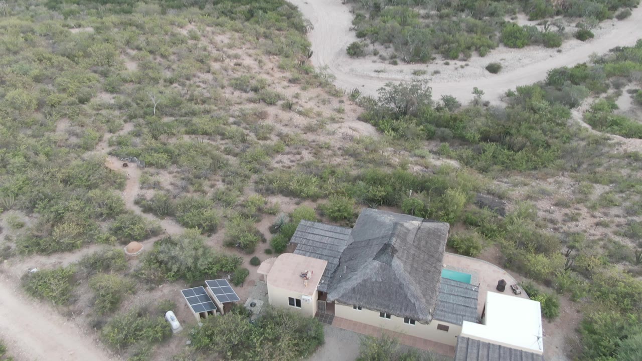 Drone view of a desert property with solar panels and brush