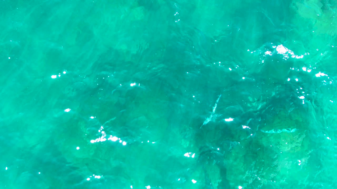 Turquoise ocean surface over dark underwater rocks
