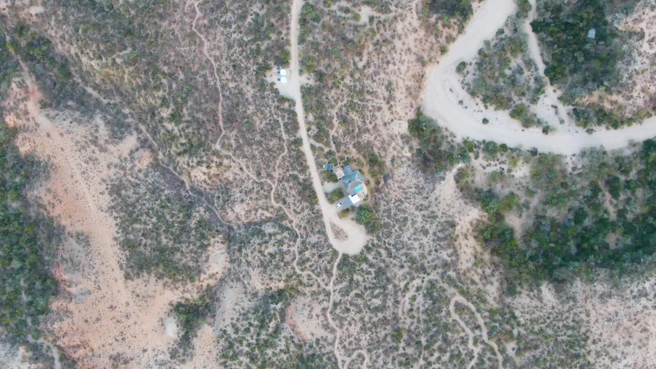 Aerial view of pale road looping through dry scrubland