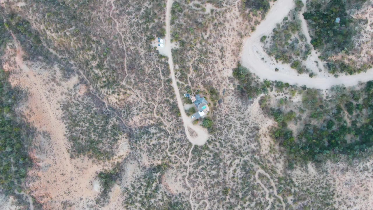 High overhead view of a dirt road cutting through dry scrub hills.