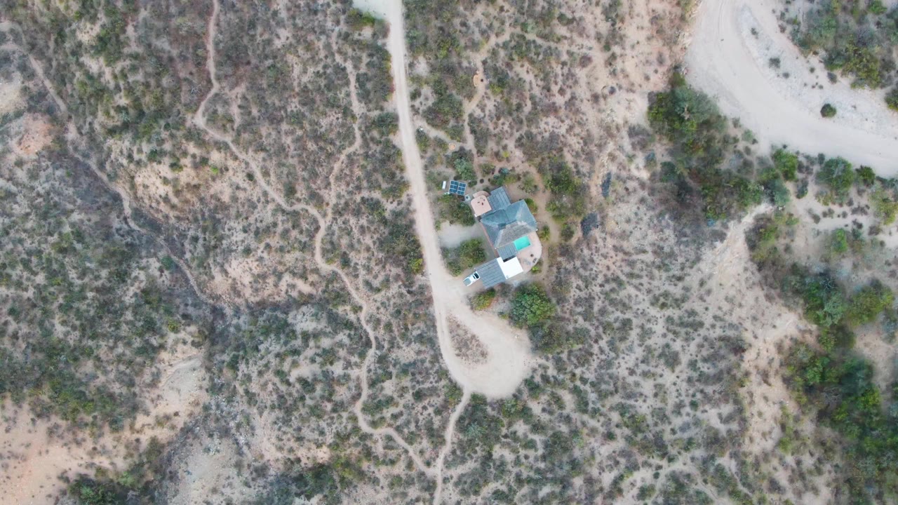 Aerial view of a small building beside a curved dirt road.
