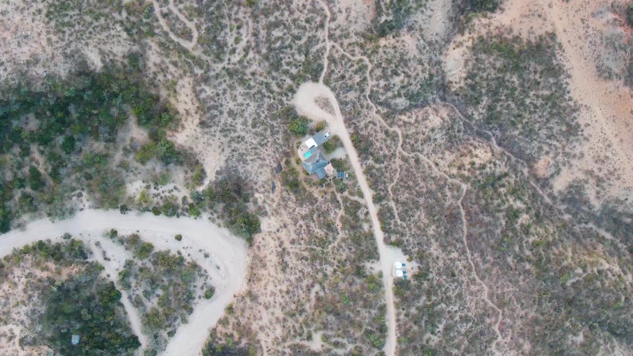 At one second, the Cabo Pulmo aerial view keeps the winding pale road prominent against dry scrub-covered terrain, with no visible people.