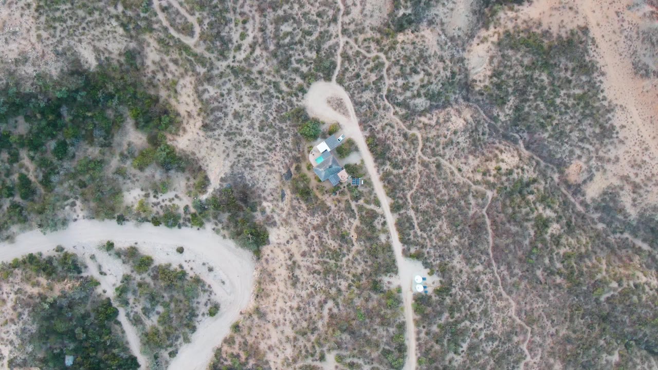 Aerial view of a pale road curving through sparse desert brush