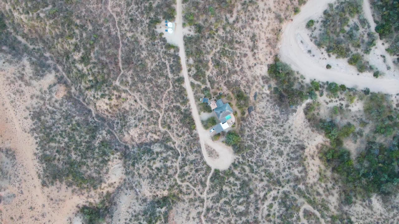 Winding dirt road and desert wash near a small building