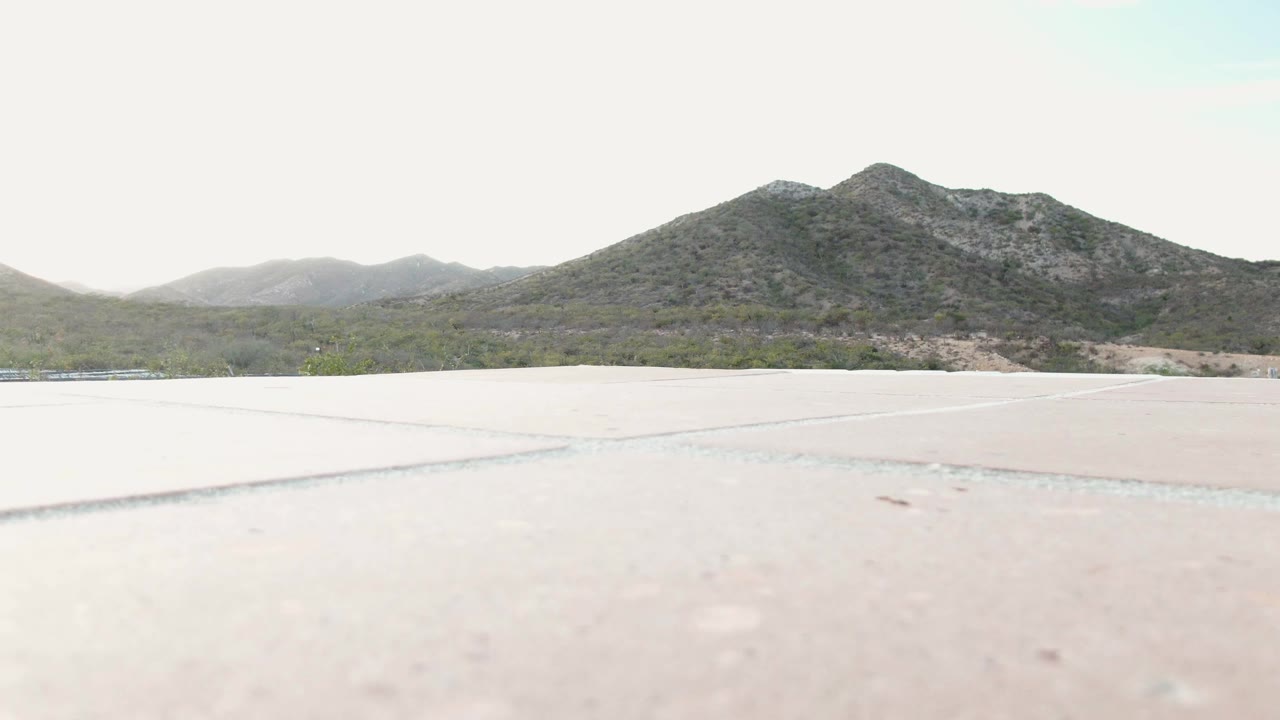 Cabo Pulmo, Baja California Sur frame with the concrete plane taking most of the lower view and a green-gray mountain ridge beyond sparse terrain, with no visible people.