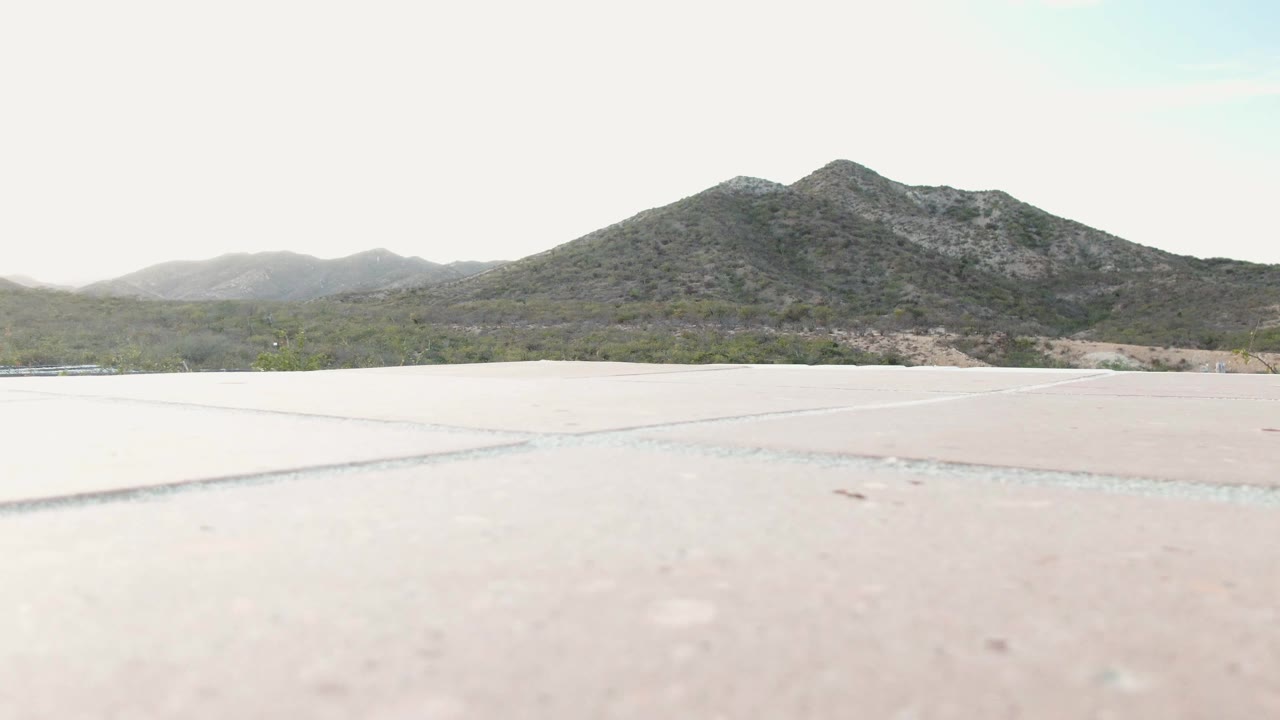 Pale pavement leading toward scrubland and a mountain ridge