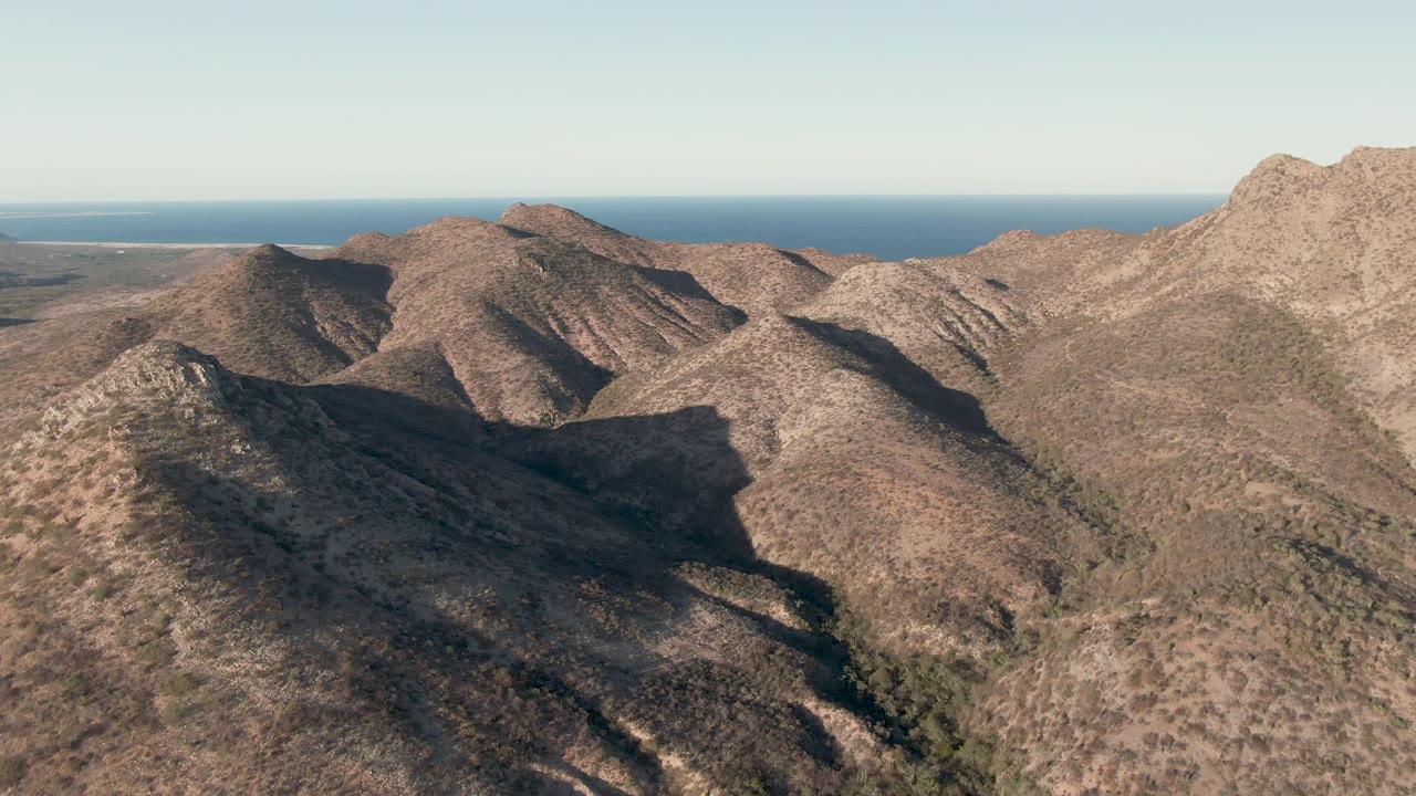Aerial view of dry mountain ridges with ocean on the horizon