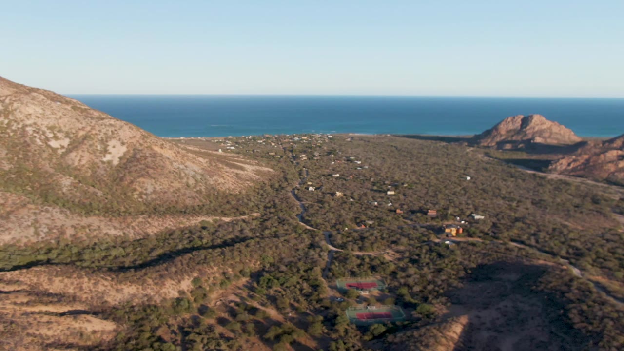 Hillside settlement with dirt roads and ocean beyond