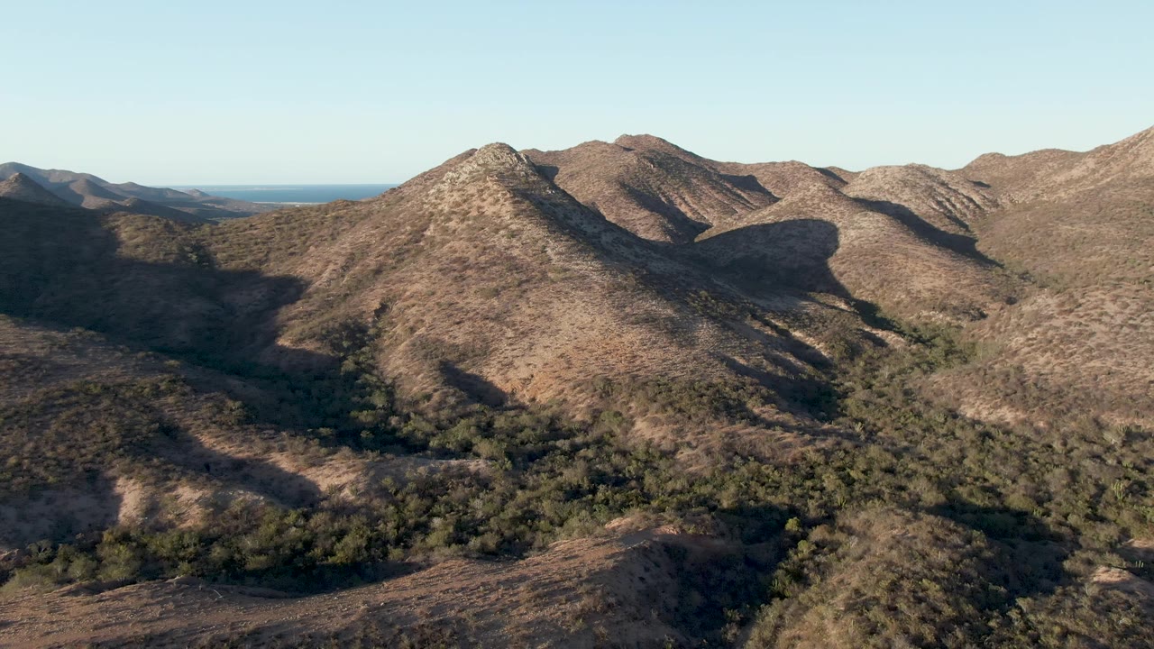 Brown mountain ridge above shaded valley greenery.