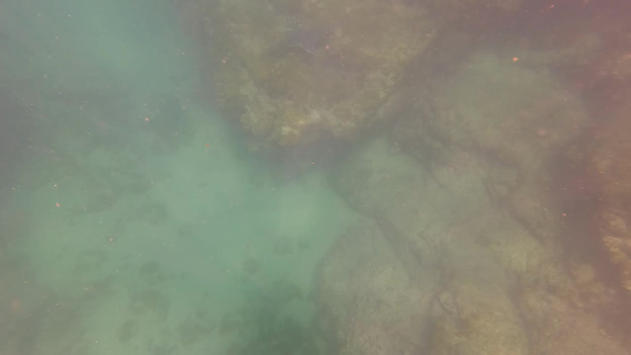 Cloudy turquoise water beside underwater rocks
