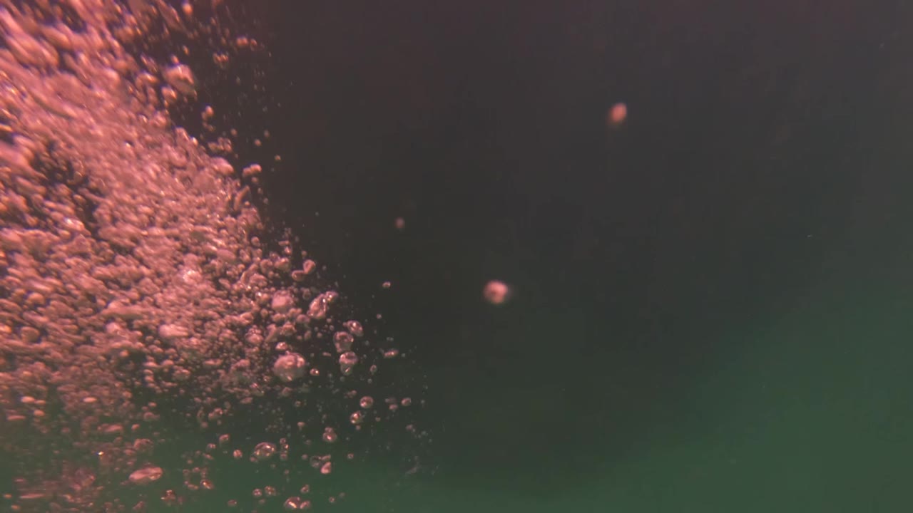 Rising bubbles fill the left side of a green underwater view in San Jose Del Cabo, Baja California Sur, with no visible people.