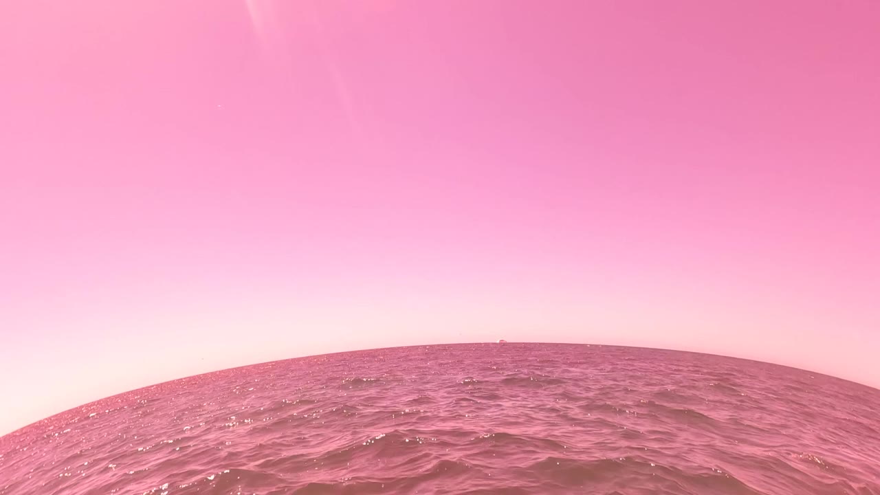 Pink-tinted ocean surface with sun glow