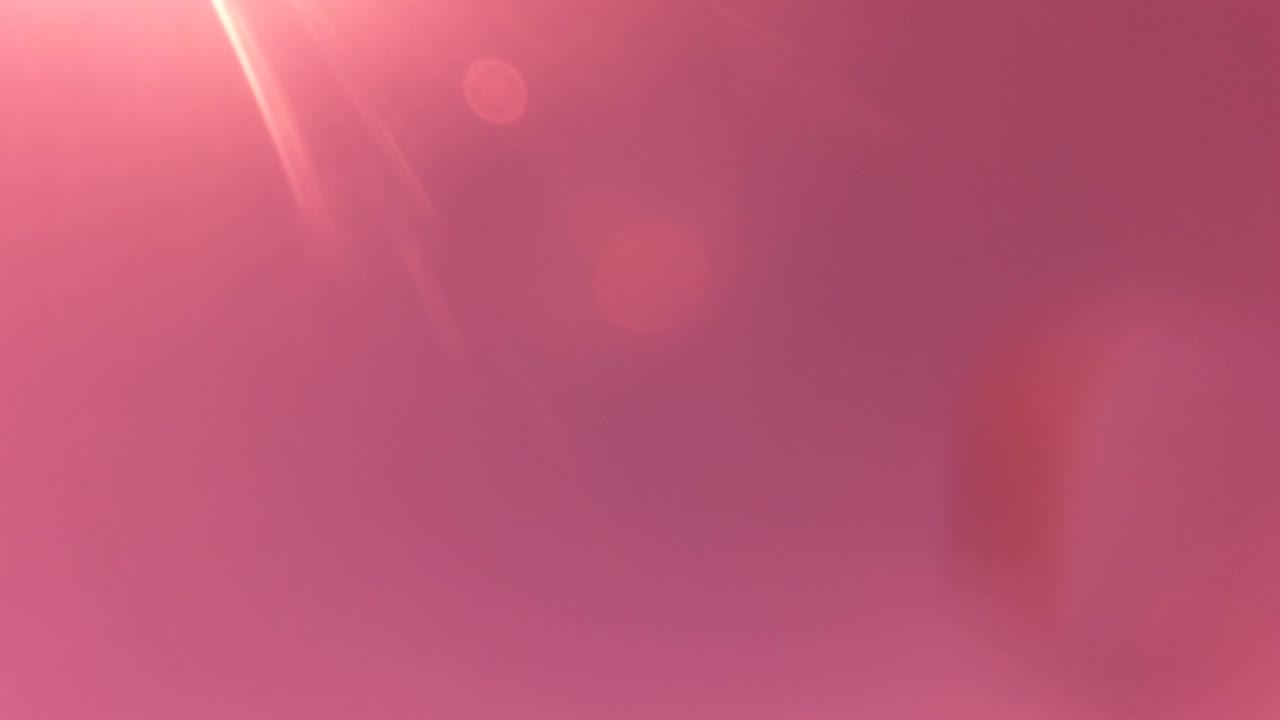 Pink and purple tinted opening frame in San Jose del Cabo with bright sun flare, hazy sky, soft lens droplets, and no visible people.