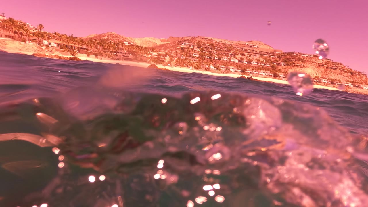 Low ocean surface with bubbles and distant coastline.