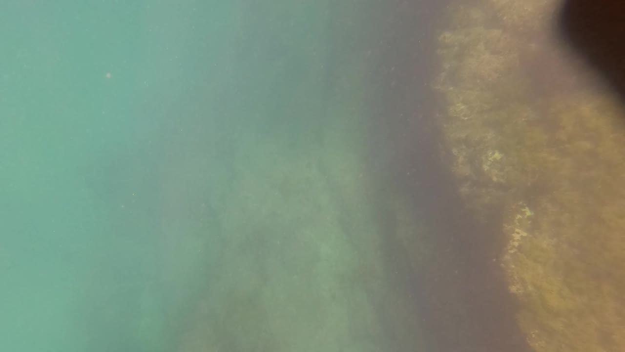 Underwater seabed with turquoise water and a darker vertical shadow.