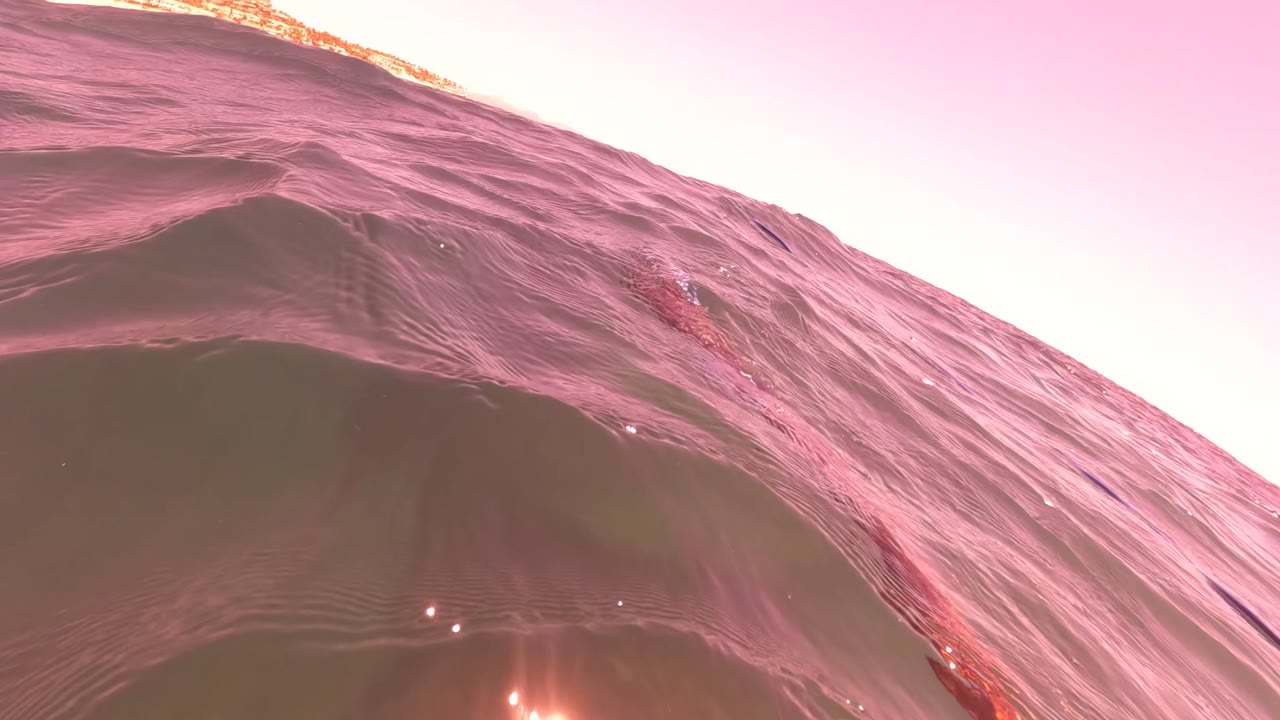 Reddish-pink rippled surface water in San Jose Del Cabo with bright sun glare near the lower edge and no visible people.