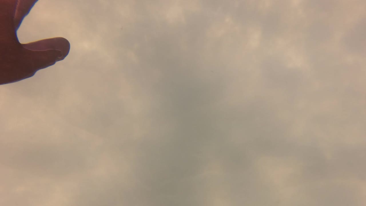 The hand is cropped along the top edge as clear water below shows shifting caustic patterns and diffuse warm-green tones in San Jose Del Cabo.