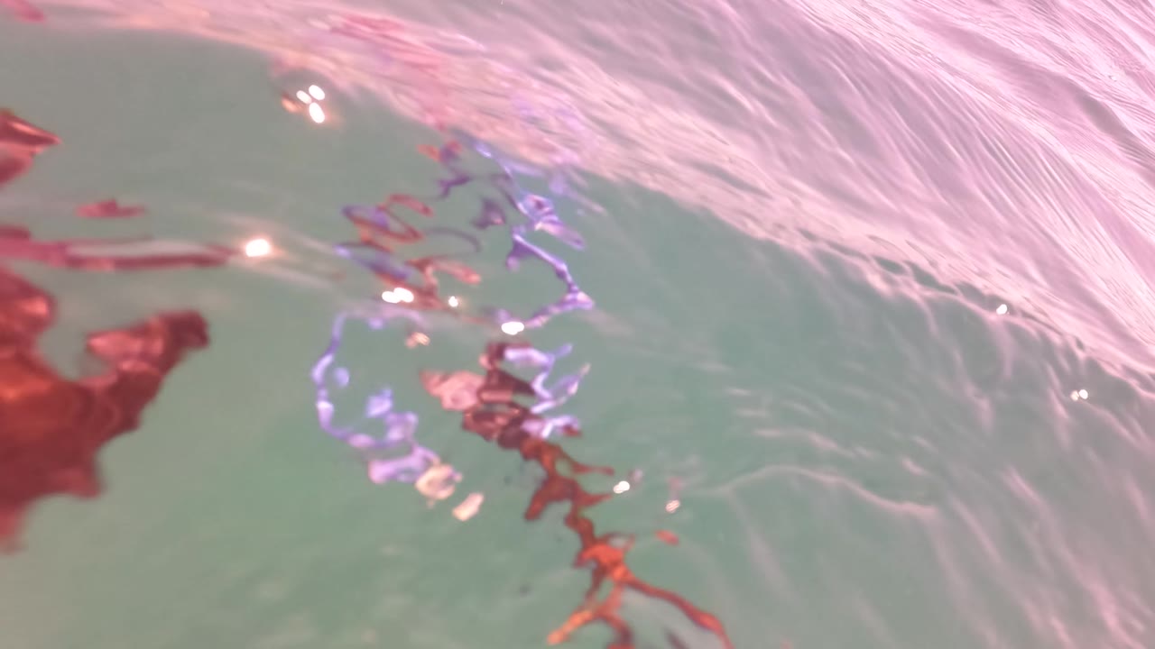Underwater view of the rippled surface in San Jose del Cabo, Baja California Sur, with red shapes or reflections near the top and no visible people.