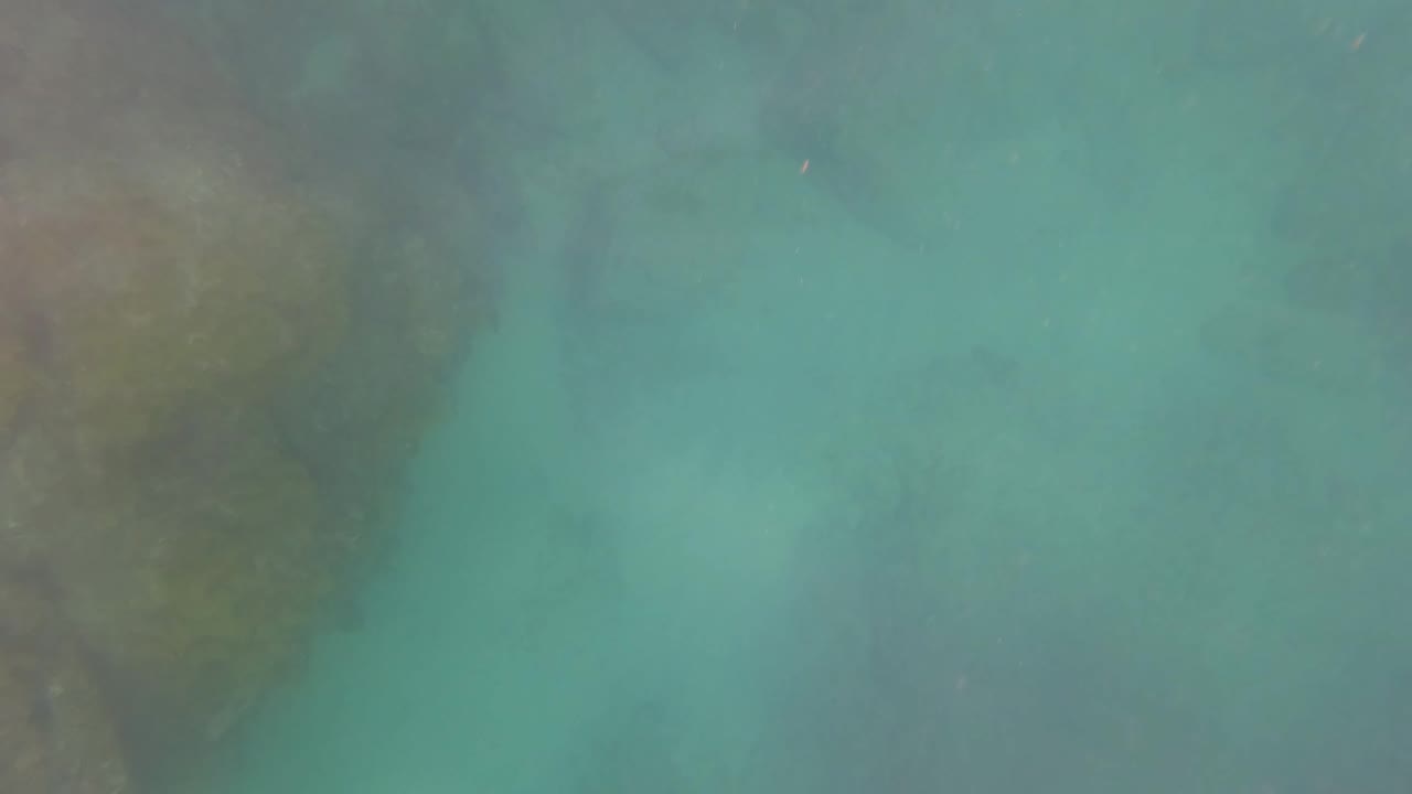 Underwater rocks fade into turquoise water in San Jose Del Cabo, Baja California Sur, with no visible people or fishing gear yet prominent.